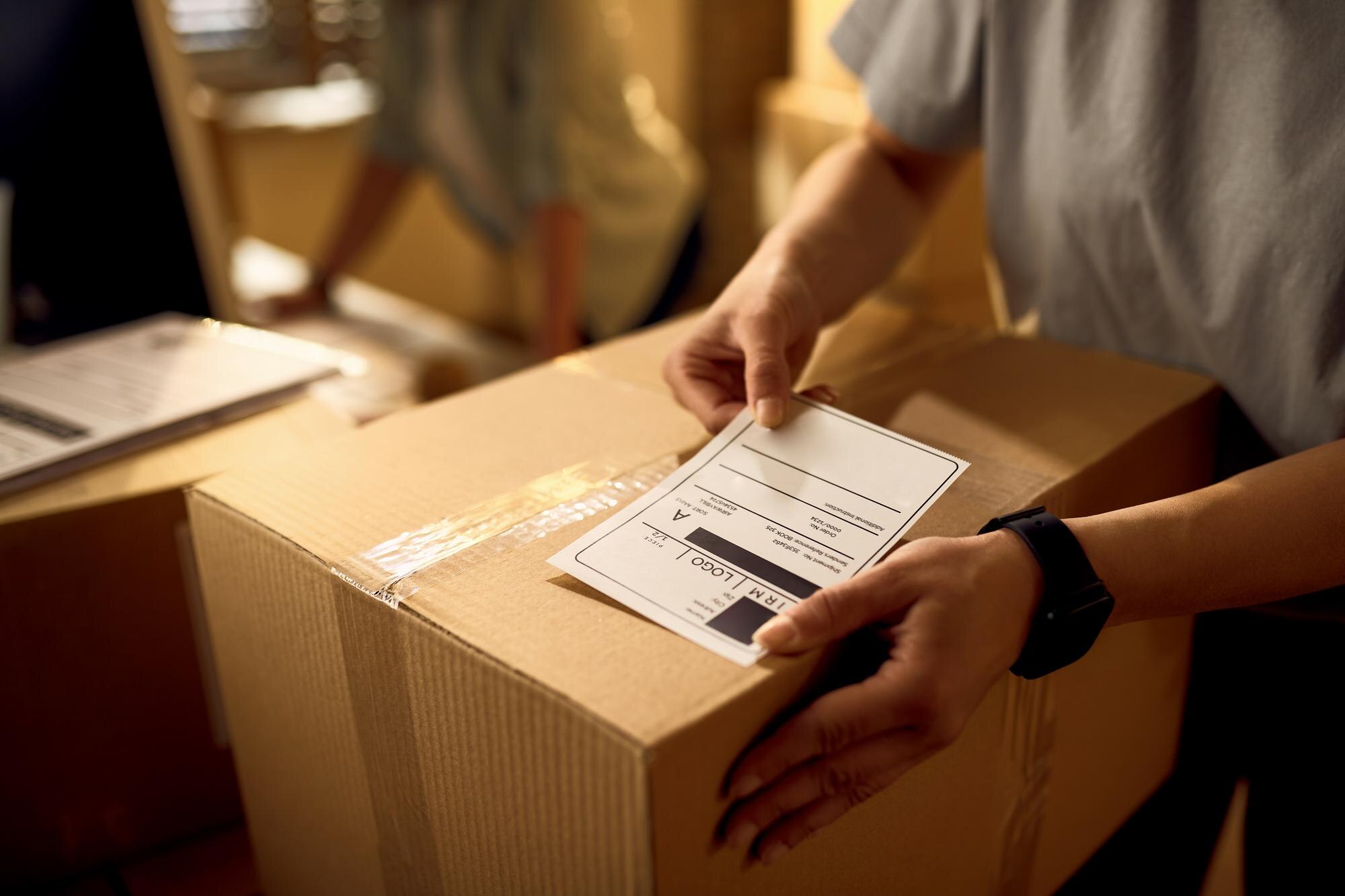 closeup-courier-attaching-address-label-package-while-working-office_637285-6592